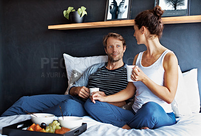 Buy stock photo Shot of a content couple having breakfast in their bedroom