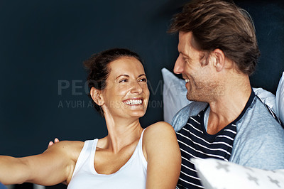 Buy stock photo Shot of a content mature couple laughing together while sitting in bed
