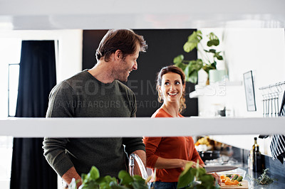 Buy stock photo Shot of a smiling mature couple cooking together in their kitchen