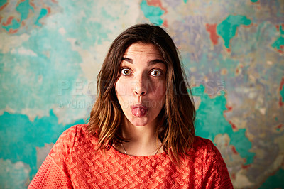 Buy stock photo Portrait of a young woman standing in front of a peeling wall sticking out her tongue