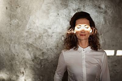 Buy stock photo Shot of a mature businesswoman with a beam of sunlight across her closed eyes