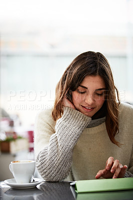 Buy stock photo Shot of a young woman sitting in a cafe using a digital tablet