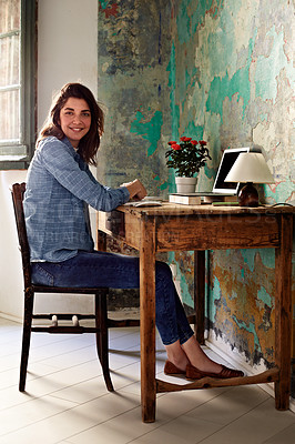 Buy stock photo Portrait of a smiling young woman sitting at a work desk at home