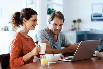 Buy stock photo Shot of a smiling couple using a laptop while eating breakfast