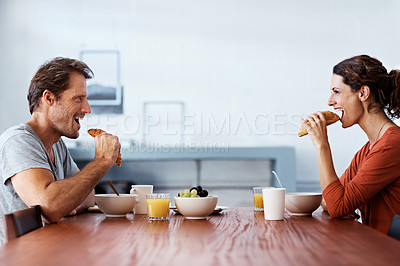Buy stock photo Shot of a smiling couple eating breakfast at their kitchen table