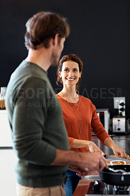 Buy stock photo Shot of a happy couple cooking together in their kitchen