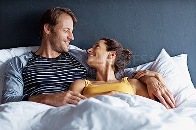 Buy stock photo Shot of a content couple lying in bed together