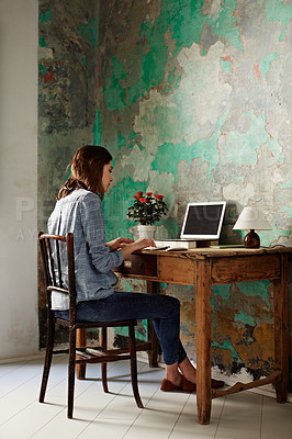 Buy stock photo Shot of a young woman sitting at a work desk at home working on a laptop