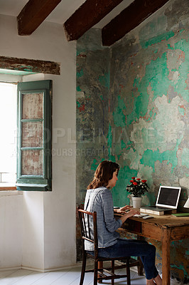 Buy stock photo Shot of a young woman sitting at a work desk at home working on a laptop