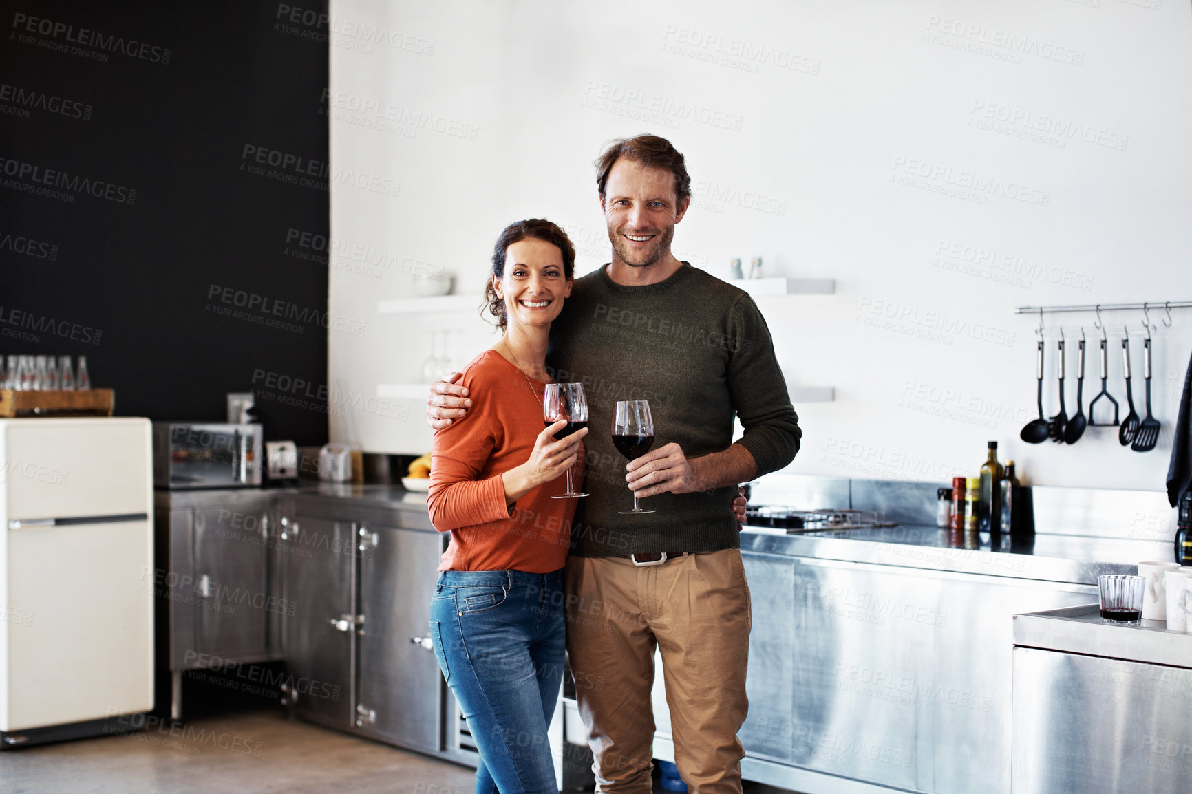 Buy stock photo Portrait of a smiling mature couple drinking wine together in their kitchen