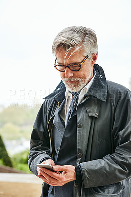 Buy stock photo Shot of a handsome mature man using a cellphone in the city