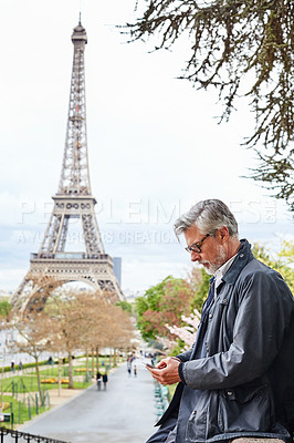 Buy stock photo Shot of a handsome mature man using a cellphone in Paris with the Eiffel Tower in the backgournd