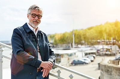 Buy stock photo Portrait of a mature man leaning on the railing of a bridge with the city in the background
