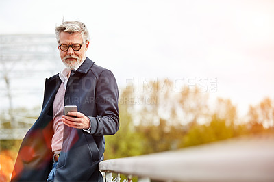 Buy stock photo Shot of a mature man using a cellphone while leaning on a railing in the city