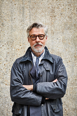 Buy stock photo Portrait of a handsome mature man standing with his arms crossed against a wall in the city
