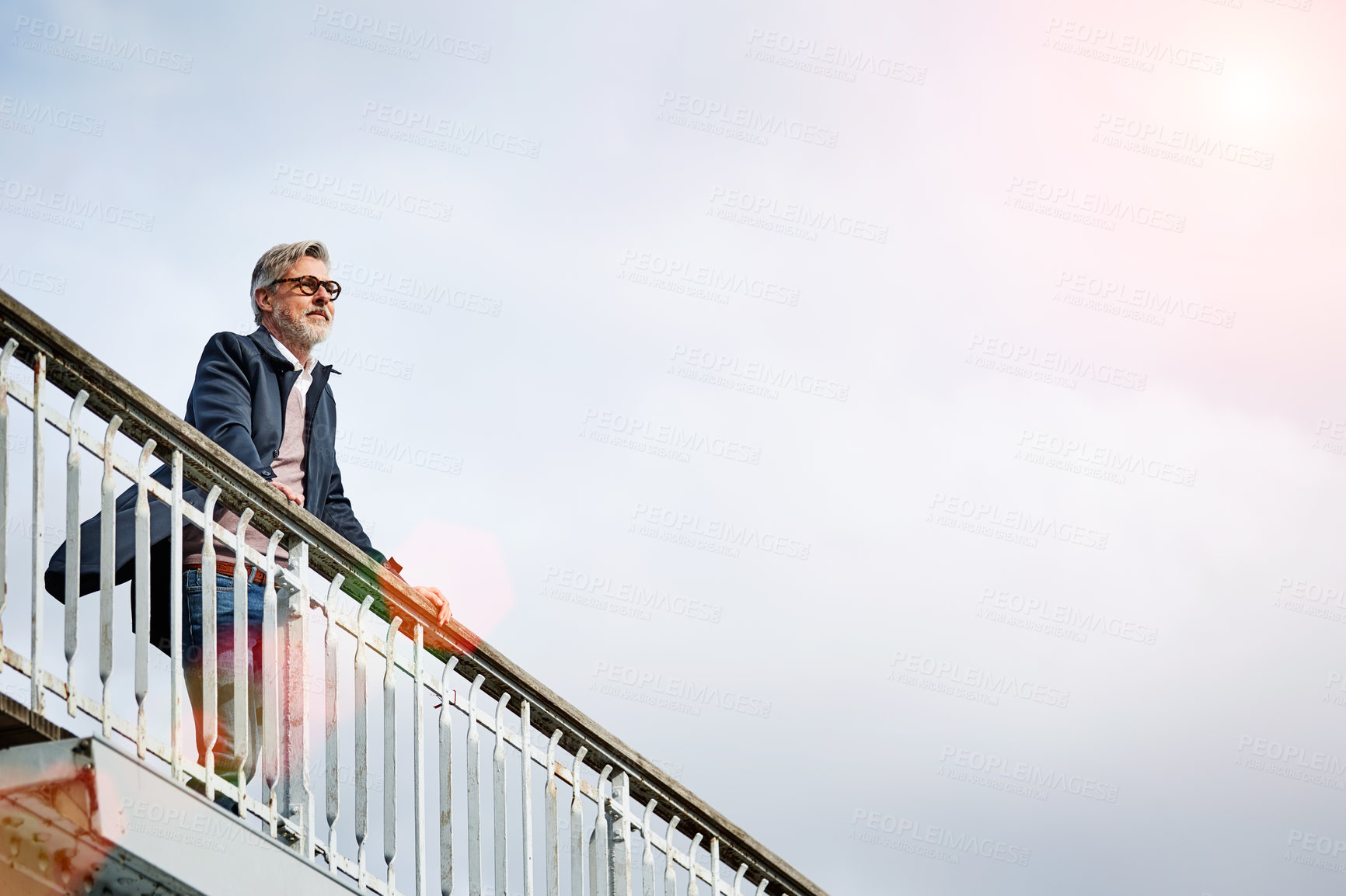 Buy stock photo Shot of a mature man admiring the view while leaning on the railing of a bridge