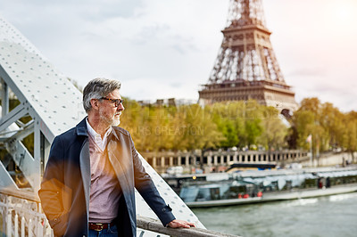 Buy stock photo Shot of a handsome mature man leaning on a railing in Paris with the Eiffel Tower in the background