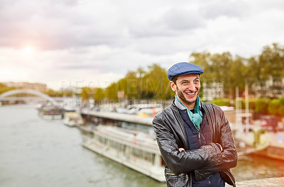 Buy stock photo Shot of a smiling young man standing on a bridge over the Seine River in Paris