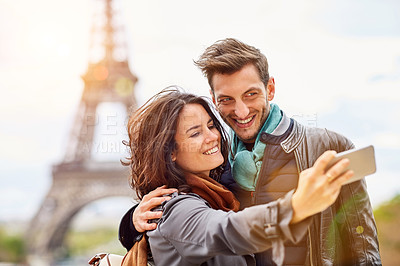 Buy stock photo Shot of a happy young couple talking a selfie together in front of the Eiffel Tower