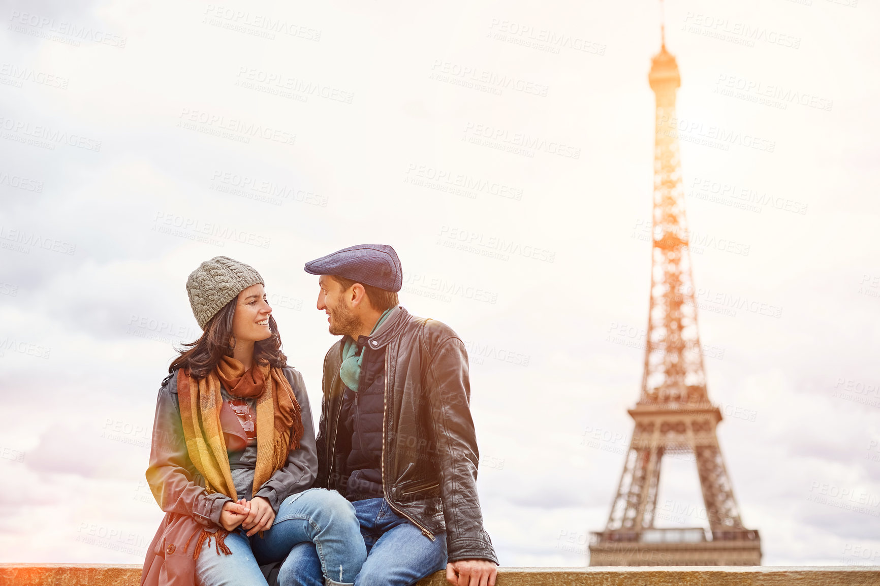 Buy stock photo Shot of a happy young couple sitting together in front of the Eiffel Tower