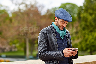 Buy stock photo Shot of a young man using a cellphone while standing on a bridge in Paris