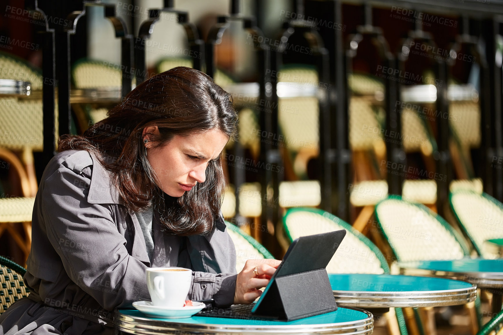 Buy stock photo Shot of a young woman sitting at a sidewalk cafe in Paris using a digital tablet