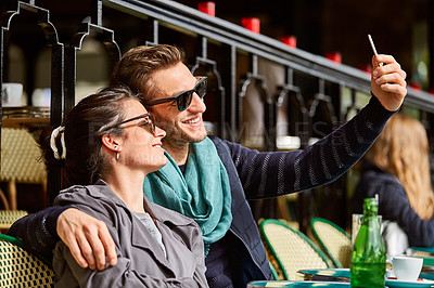 Buy stock photo Shot of a happy young couple talking a selfie together while sitting at a sidewalk cafe in Paris
