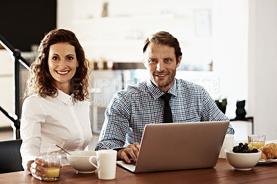 Buy stock photo Portrait of a professional couple sitting at the dining table eating breakfast and using a laptop