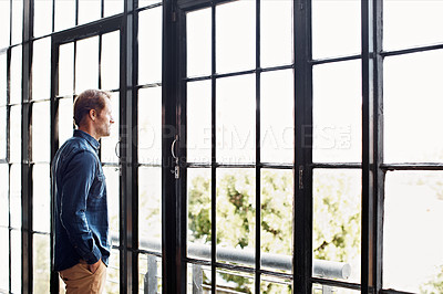 Buy stock photo Shot of a mature man deep in thought while looking through a window at home