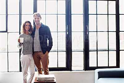 Buy stock photo Portrait of an affectionate mature couple standing in front of a window at home