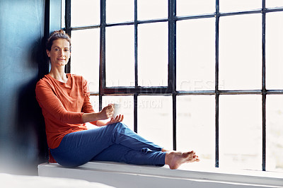 Buy stock photo Portrait of an attractive mature woman sitting on a window sill at home drinking a cup of coffee