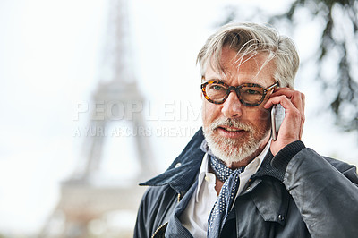 Buy stock photo Shot of a handsome mature man talking on a cellphone in Paris with the Eiffel Tower in the background