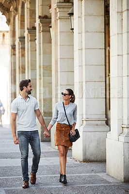 Buy stock photo Shot of an affectionate young couple walking together in the city