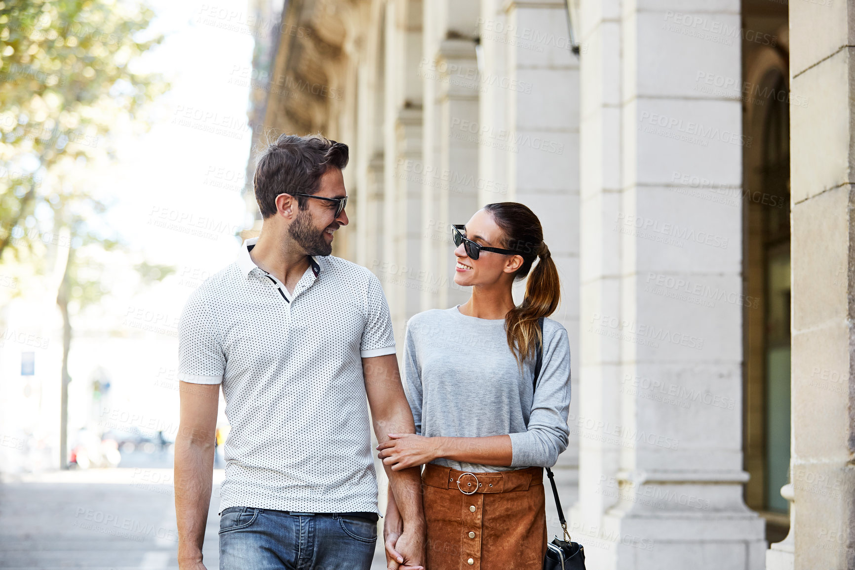 Buy stock photo Shot of an affectionate young couple walking together in the city