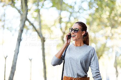 Buy stock photo Shot of a stylish young woman talking on a cellphone while walking in the city