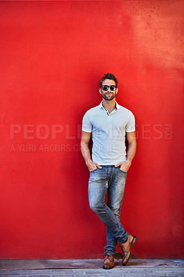 Buy stock photo Portrait of a stylish young man leaning against a red wall outside
