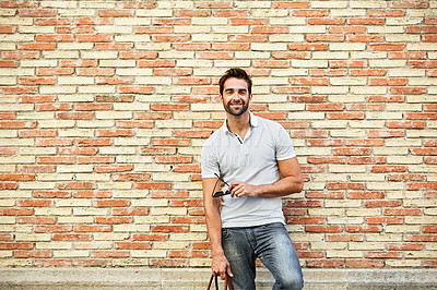 Buy stock photo Portrait of a stylish young man leaning against a brick wall outside