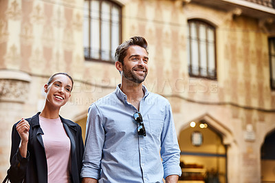 Buy stock photo Shot of an affectionate young couple walking hand in hand together in the city