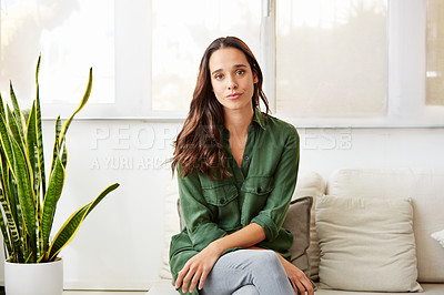 Buy stock photo Portrait of a young woman sitting on a sofa at home