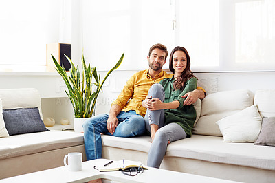 Buy stock photo Portrait of a smiling young couple relaxing on their sofa at home