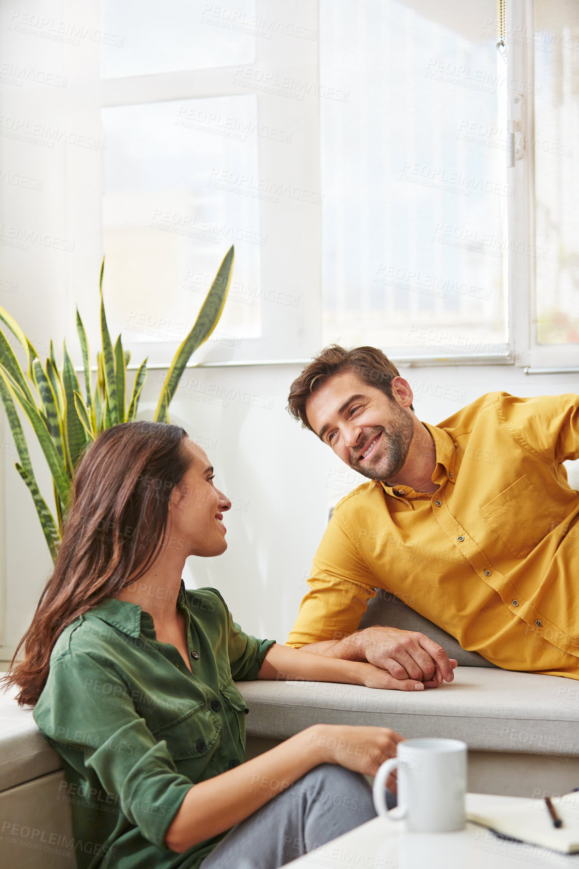 Buy stock photo Shot of a smiling young couple talking together while relaxing in their living room
