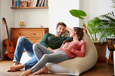 Buy stock photo Shot of a smiling young couple talking together while relaxing on a beanbag sofa at home