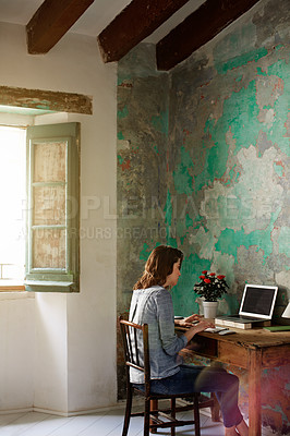 Buy stock photo Shot of a young woman sitting at a desk in her room using a computer