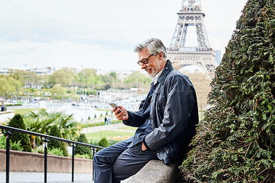 Buy stock photo Shot of a handsome mature man using a cellphone in Paris with the Eiffel Tower in the background