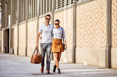Buy stock photo Shot of an affectionate young couple walking together in the city