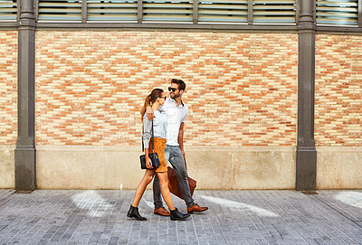 Buy stock photo Shot of an affectionate young couple walking together in the city