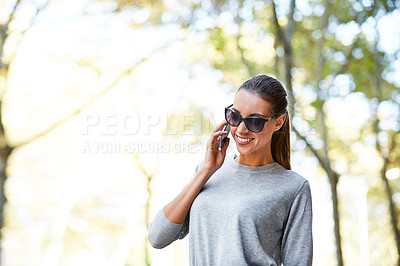 Buy stock photo Shot of a stylish young woman talking on a cellphone while walking in the city