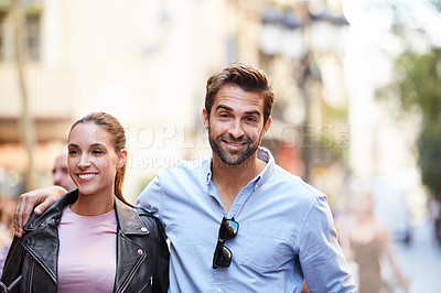 Buy stock photo Portrait of an affectionate young couple walking together in the city