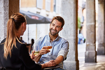 Buy stock photo Shot of a young couple sitting at a sidewalk table drinking wine and talking together
