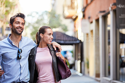 Buy stock photo Shot of an affectionate young couple walking together in the city